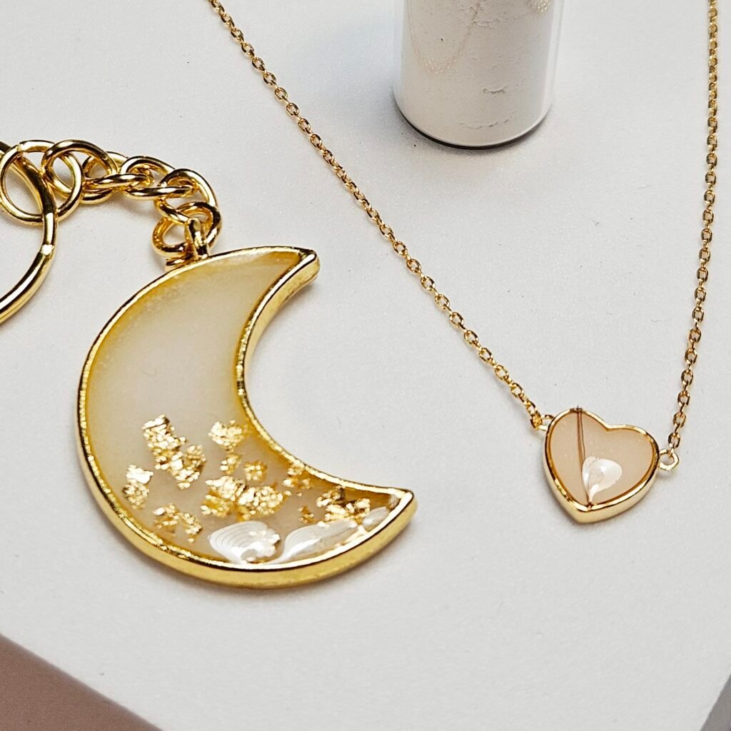 Muttermilchschmuck: Mondsichel-Anhänger mit Blattgold und Kette mit Herz-Anhänger in Gold, aus dem Workshop in Wuppertal