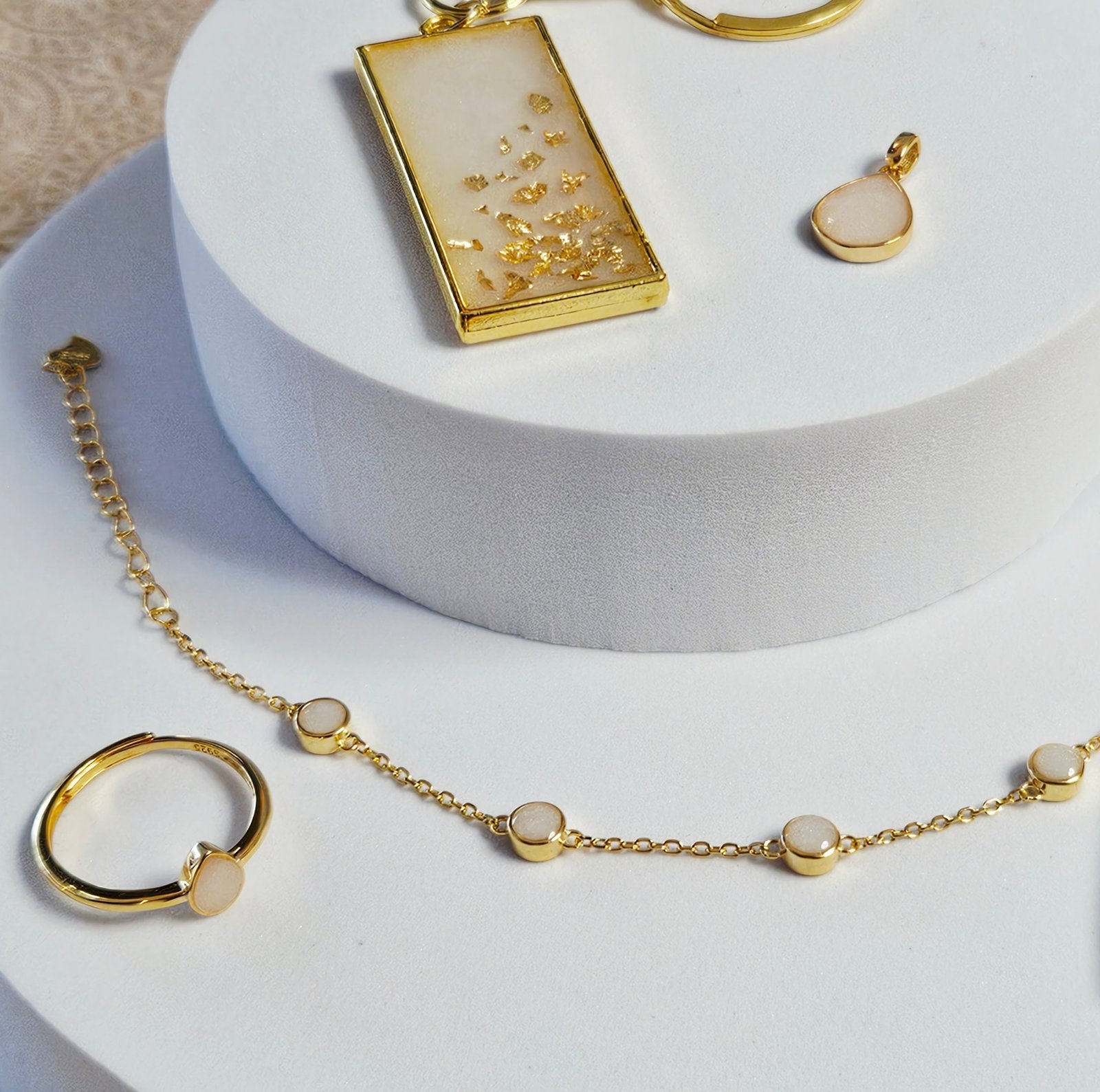 Muttermilchschmuck in Gold: rechteckiger Anhänger mit Blattgold, Tropfen-Anhänger, Ring und Armband mit runden Fassungen, aus dem Workshop in Wuppertal