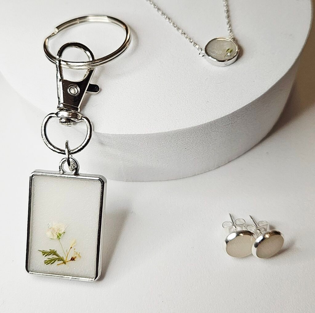 Muttermilchschmuck in Silber: Schlüsselanhänger mit getrockneten Blüten, Kette und Ohrstecker, aus dem Workshop in Wuppertal