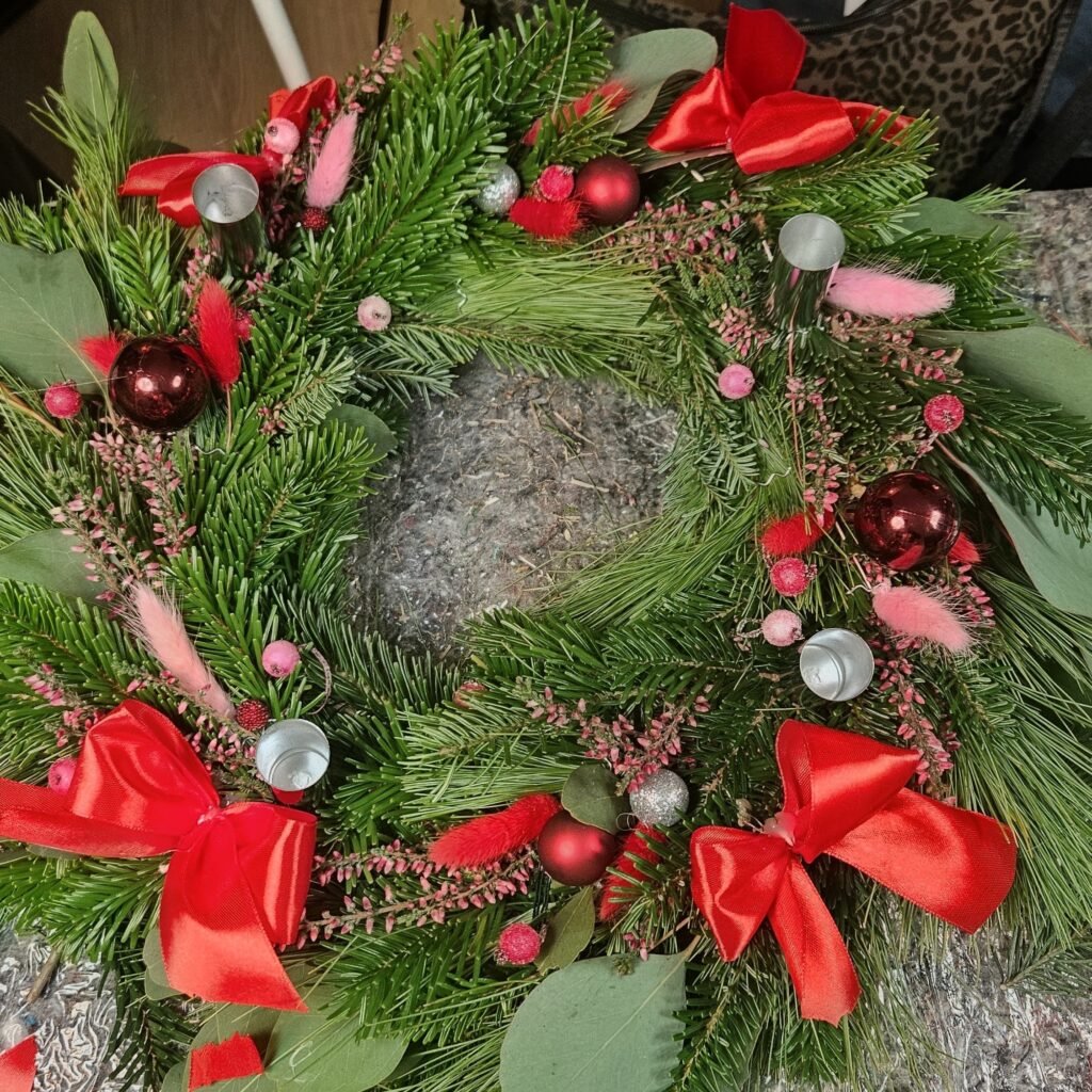 Adventskranz in klassischem Rot mit Schleifen, roten Kugeln, Heidekraut und Trockengräsern, aus dem Workshop Adventskranz binden in Wuppertal