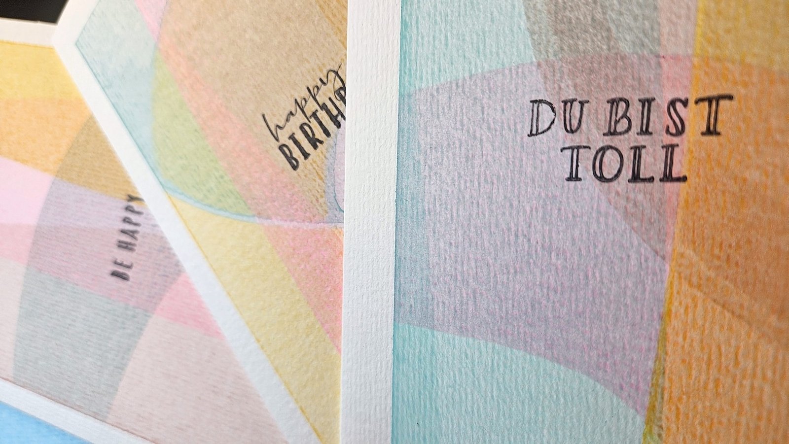 Mehrere handbemalte Grußkarten in Pastelltönen mit Schriftzügen wie „Du bist toll" und „happy birthday", aus dem DIY-Style-Cards-Workshop von Chris B.Art in Wuppertal