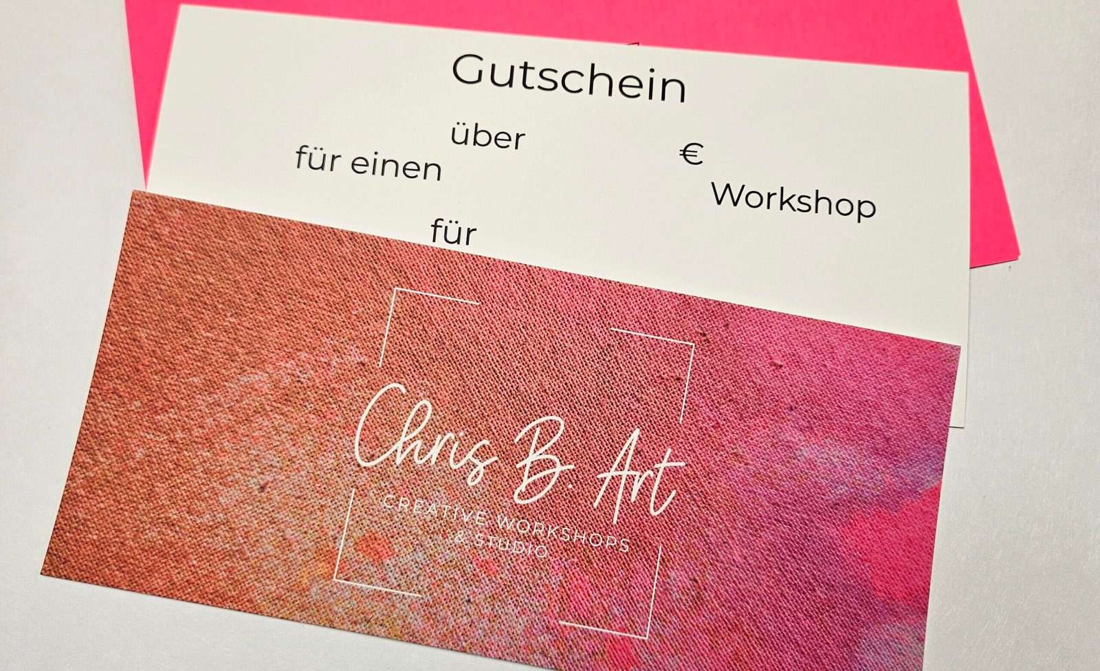Gutschein für einen Workshop bei Chris B.Art, Vorder- und Rückseite mit Logo auf pink-orangem Farbverlauf, dahinter ein pinker Umschlag