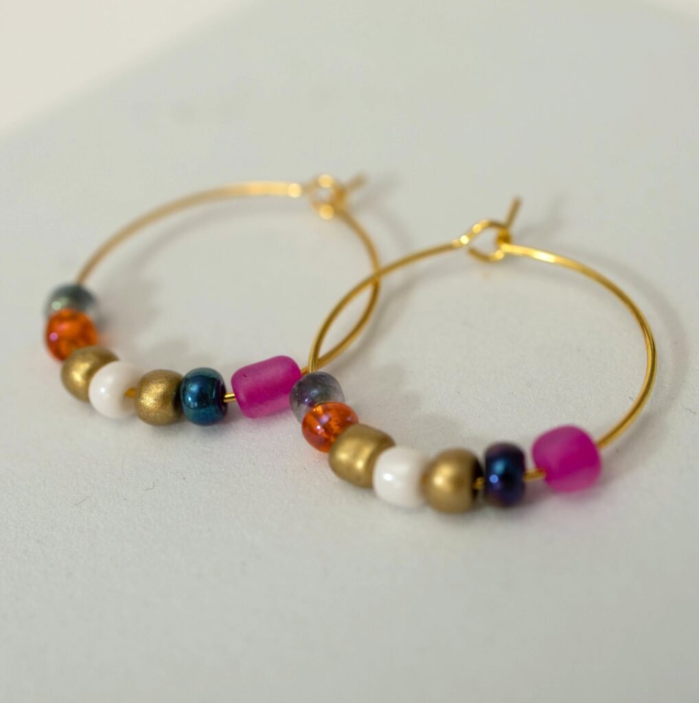 Selbstgefädelte goldene Creolen mit Perlen in Gold, Cremeweiß, Orange, Blau und mattem Pink