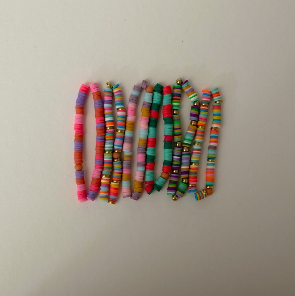 Viele bunte Perlenarmbänder in Pink, Mint, Petrol und Regenbogenfarben nebeneinander aufgereiht