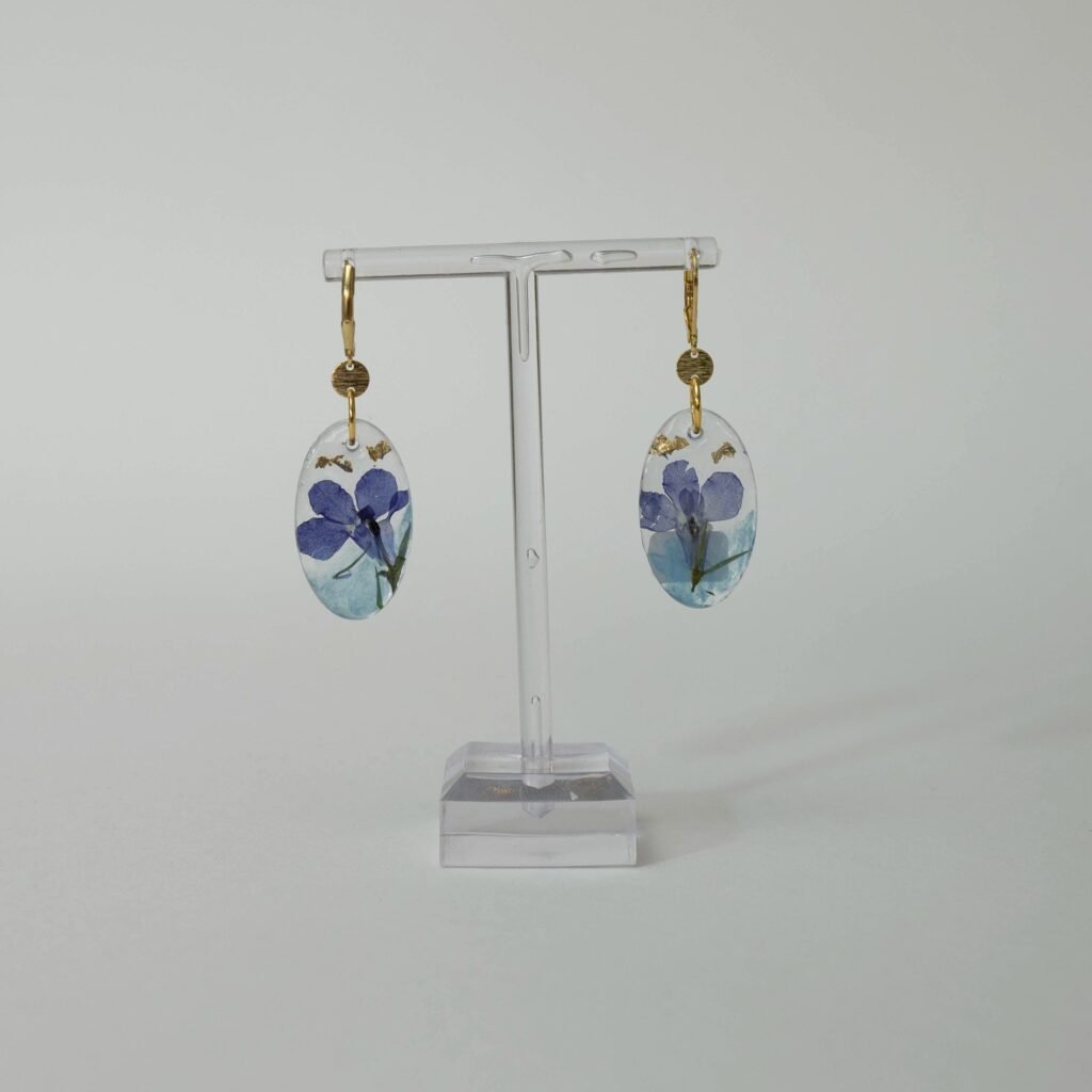 Ovale UV-Resin Ohrringe mit blauer Trockenblüte auf türkisem Grund und Blattgold, aus dem Schmuck-Workshop in Wuppertal
