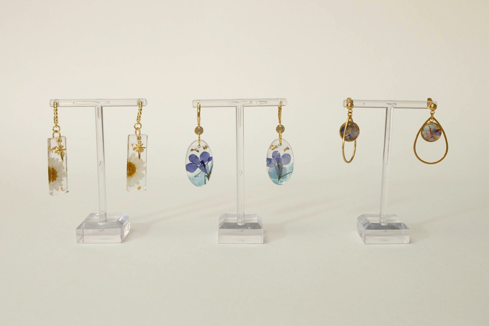 Drei Paar UV-Resin Ohrringe mit Margeriten, blauen Blüten und Perlmutt-Flakes in Gold, aus dem Schmuck-Workshop von Chris B.Art in Wuppertal